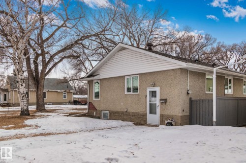 Residence featuring a stucco exterior with a stone-finish foundation, white trim, and a gabled roof - 12002 37 Street, Edmonton, AB 