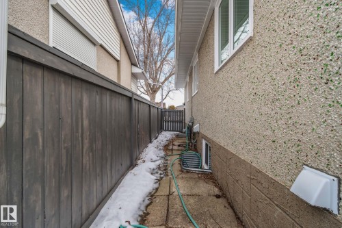 Side yard access featuring a wood privacy fence and a paved pathway - 12002 37 Street, Edmonton, AB 