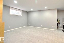 Spacious room featuring light gray walls, recessed ceiling lighting, and light-colored carpeting - 