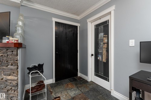 The property features an entryway with slate tile flooring, a black paneled door, and a white door with decorative glass inserts - 203 10003 87 Avenue, Edmonton, AB - Indoor Photo Showing Other Room
