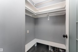 Walk-in closet with multi-level shelving, integrated hanging rods, and a white corner bench - 