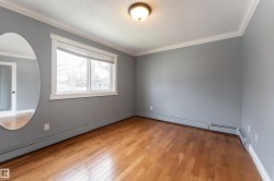 Room featuring wood-finish flooring, a window with white trim, baseboard heating, gray painted walls, and crown molding - 