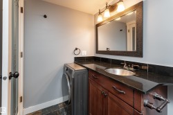 Bathroom vanity featuring a dark stone countertop, undermount sink, and rich wood cabinetry - 