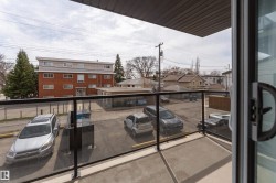 Balcony featuring a concrete floor, dark metal railing, and clear glass panels - 