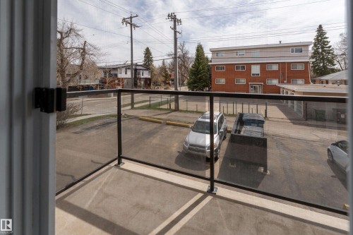 Balcony featuring glass panel railing with dark-toned metal framing, concrete flooring, and a sliding door - 203 10003 87 Avenue, Edmonton, AB - Outdoor