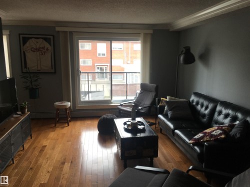 Living area featuring hardwood floors, a sliding glass door, and crown molding - 203 10003 87 Avenue, Edmonton, AB - Indoor Photo Showing Living Room