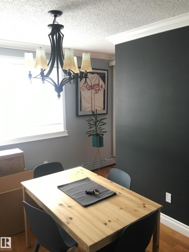 Dining area with hardwood flooring, a dark accent wall, and a traditional style chandelier - 203 10003 87 Avenue, Edmonton, AB - Indoor Photo Showing Dining Room