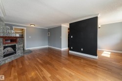 Living area featuring wood-finish flooring, a stone-clad fireplace with a wood mantle and glass block accents, and a partial wall separating spaces - 