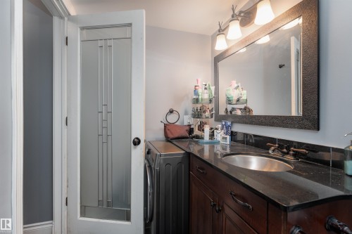 Bathroom vanity with an undermount sink, dark countertop, and a large mirror with an ornate frame - 203 10003 87 Avenue, Edmonton, AB - Indoor Photo Showing Bathroom