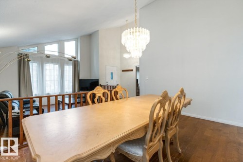 Formal dining area featuring a tiered crystal chandelier, wood-finish flooring, and high vaulted ceilings - 4340 33 Street, Edmonton, AB - Indoor Photo Showing Dining Room