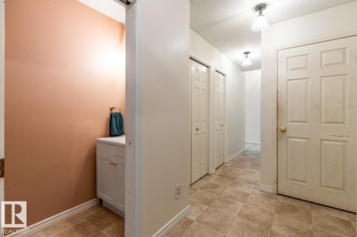 Hallway featuring neutral-toned floor tiling, two flush-mount ceiling light fixtures, and a white paneled door - 4340 33 Street, Edmonton, AB - Indoor Photo Showing Other Room