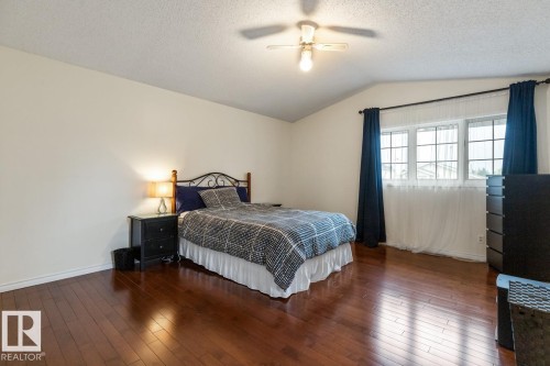 Vaulted ceiling with an attached ceiling fan, hardwood flooring, and a large window with white muntins - 4340 33 Street, Edmonton, AB - Indoor Photo Showing Bedroom
