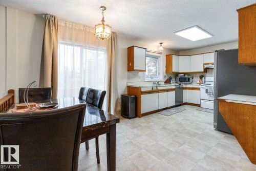 Combined dining and kitchen area featuring wood-finish cabinetry, white countertops, and light-toned tile flooring - 4340 33 Street, Edmonton, AB - Indoor Photo Showing Kitchen With Double Sink