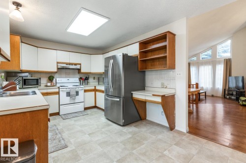 Kitchen featuring light-toned flooring and white cabinetry with wood-finish trim - 4340 33 Street, Edmonton, AB - Indoor Photo Showing Kitchen With Double Sink