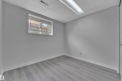 Bright room featuring light gray wood-finish flooring, white baseboards, and a window with security bars - 
