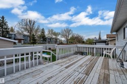 Expansive outdoor wooden deck with white railing, offering ample space - 
