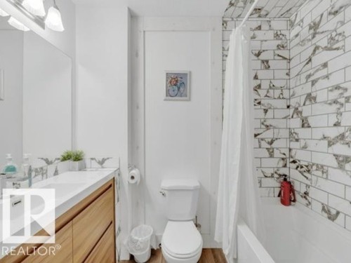Bathroom featuring a wood-finish vanity with an integrated sink and modern faucet - 3602 50Th Ave, Sylvan Lake, AB - Indoor Photo Showing Bathroom
