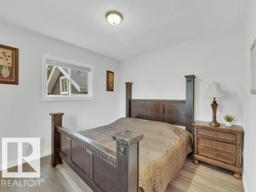 Interior room featuring wood-finish flooring, white walls, and a single window with blinds - 3602 50Th Ave, Sylvan Lake, AB - Indoor Photo Showing Bedroom