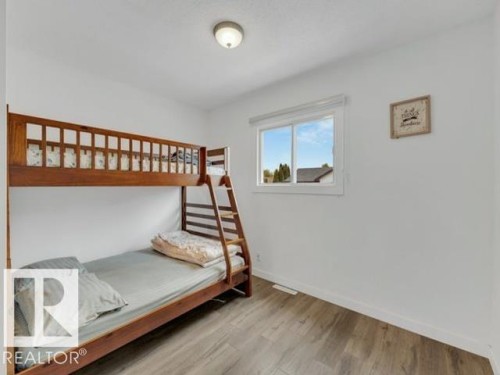 Room featuring wood-finish flooring, a window with white trim, and a ceiling light fixture - 3602 50Th Ave, Sylvan Lake, AB - Indoor Photo Showing Bedroom