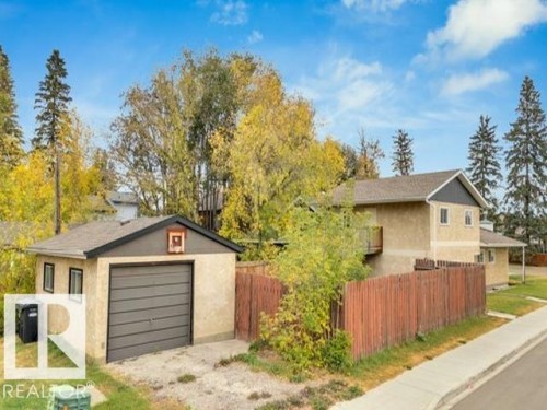 Detached garage with a dark sectional door, stucco exterior, and two side windows - 3602 50Th Ave, Sylvan Lake, AB - Outdoor