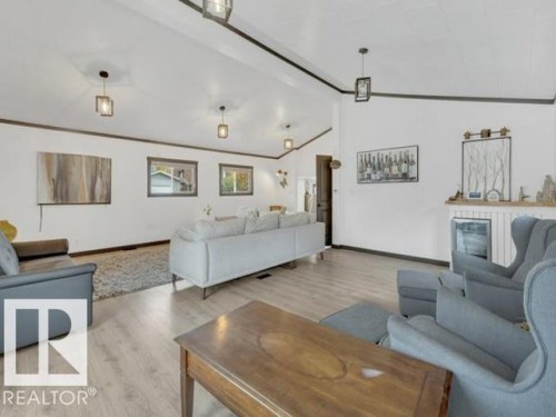 Spacious living area featuring light wood-finish flooring and a vaulted ceiling with dark trim - 3602 50Th Ave, Sylvan Lake, AB - Indoor