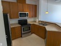 Kitchen featuring wood-finish cabinetry, speckled countertops, and stainless steel appliances including an electric range and built-in microwave - 419 4304 139 Avenue, Edmonton, AB  - Indoor Photo Showing Kitchen With Double Sink 
