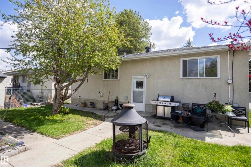 Rear exterior with stucco siding and a white entry door - 10428 68 Avenue, Edmonton, AB - Outdoor