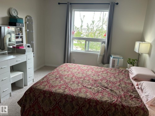 Carpeted room with a double-hung window featuring a dark rod and grey curtains - 1228 9363 Simpson Drive, Edmonton, AB - Indoor Photo Showing Bedroom