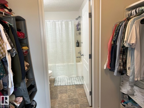 Bathroom featuring a white tub, shower with a clear curtain, and tile flooring - 1228 9363 Simpson Drive, Edmonton, AB - Indoor With Storage