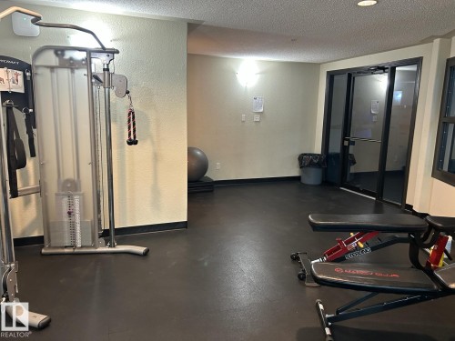 Dedicated fitness space featuring rubber flooring, a cable weight machine, and an adjustable utility bench - 1228 9363 Simpson Drive, Edmonton, AB - Indoor Photo Showing Gym Room