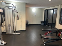 Dedicated fitness space featuring rubber flooring, a cable weight machine, and an adjustable utility bench - 
