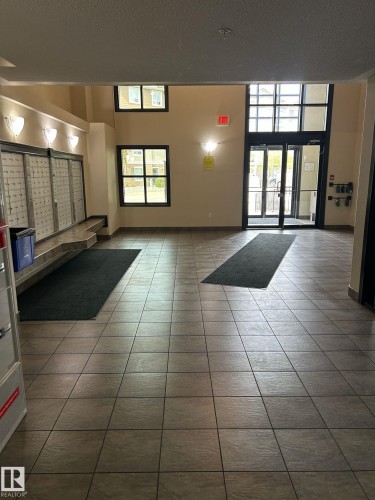 Spacious building entrance featuring tiled flooring, a wall of mailboxes, and large windows providing natural light - 1228 9363 Simpson Drive, Edmonton, AB - Indoor Photo Showing Other Room