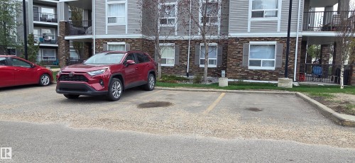 Paved parking area fronting a multi-story building featuring stone veneer and light-colored siding - 1228 9363 Simpson Drive, Edmonton, AB - Outdoor