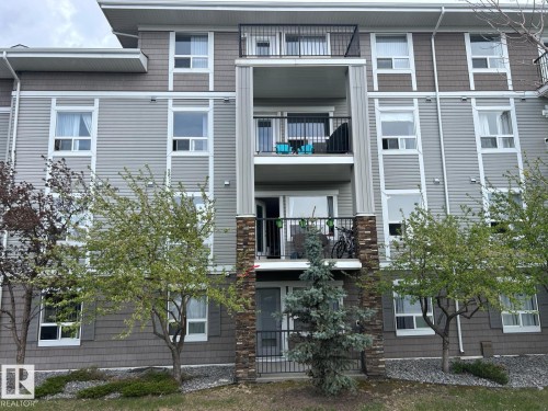 Multi-level residential building featuring balconies with black metal railings, light grey horizontal siding, and brown shake siding accents - 1228 9363 Simpson Drive, Edmonton, AB - Outdoor With Facade