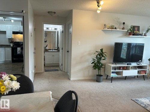 Carpeted living area featuring track lighting and wall-mounted shelving - 1228 9363 Simpson Drive, Edmonton, AB - Indoor