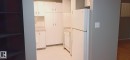 Kitchen featuring white cabinetry, light-toned countertops, tile flooring, and white appliances including a refrigerator and dishwasher - 2554 79 Street, Edmonton, AB  - Indoor 