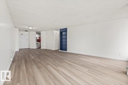 Spacious room with wood-finish flooring, white walls, and a built-in navy blue shelving unit - 