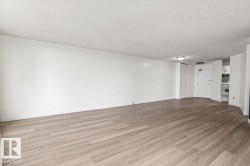 Spacious room with wood-finish flooring, white walls, and a recessed ceiling light - 