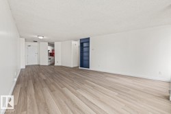 Open-concept living area featuring light wood-finish flooring, white painted walls, and a built-in blue shelving unit - 