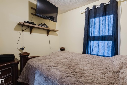 Wall-mounted television with a wood-finish shelf - 10834 75 Avenue, Edmonton, AB - Indoor Photo Showing Bedroom
