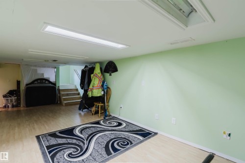 Spacious interior area featuring light-toned wood-finish flooring, recessed fluorescent lighting, and light green painted walls - 10834 75 Avenue, Edmonton, AB - Indoor