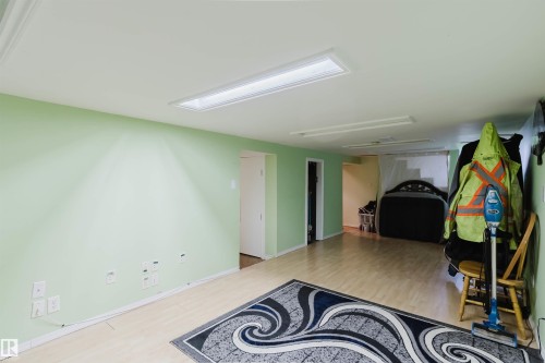 Spacious room featuring light green walls, wood-finish flooring, and recessed ceiling lighting - 10834 75 Avenue, Edmonton, AB - Indoor