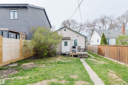 The rear exterior features a light-colored stucco finish, a wooden deck with steps, and a concrete pathway - 10834 75 Avenue, Edmonton, AB - Outdoor