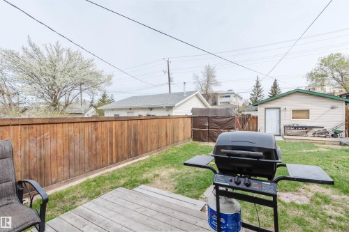 Fenced backyard featuring a wood deck, manicured lawn, and detached garage - 10834 75 Avenue, Edmonton, AB - Outdoor With Deck Patio Veranda
