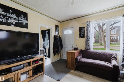 Living area featuring light-toned walls, crown molding, and wood-finish flooring - 10834 75 Avenue, Edmonton, AB - Indoor