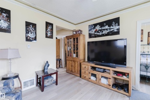 Living area featuring light wood-finish flooring, light-toned walls, and crown molding - 10834 75 Avenue, Edmonton, AB - Indoor Photo Showing Living Room