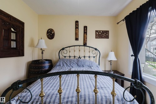 Room with light yellow walls and a large window featuring dark fabric curtains - 10834 75 Avenue, Edmonton, AB - Indoor Photo Showing Bedroom