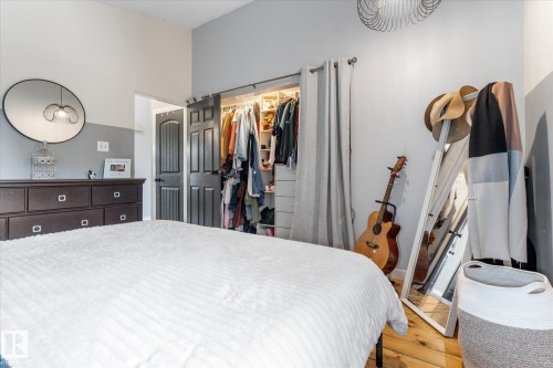 Bedroom featuring a closet with sliding barn doors, natural wood-finish flooring, and a contemporary light fixture - 4759 48 Street, Onoway, AB - Indoor Photo Showing Bedroom