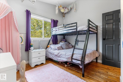 Bedroom featuring wood-finish flooring, a window with exterior tree views, and a paneled interior door - 4759 48 Street, Onoway, AB - Indoor Photo Showing Bedroom