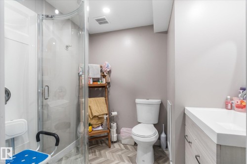 Bathroom featuring a glass-enclosed shower, white toilet, and a light wood-finish vanity with an integrated sink - 4759 48 Street, Onoway, AB - Indoor Photo Showing Bathroom